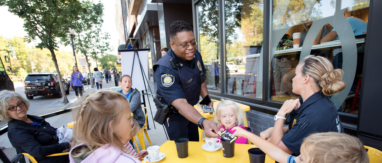 Police officer greeting adults and children.