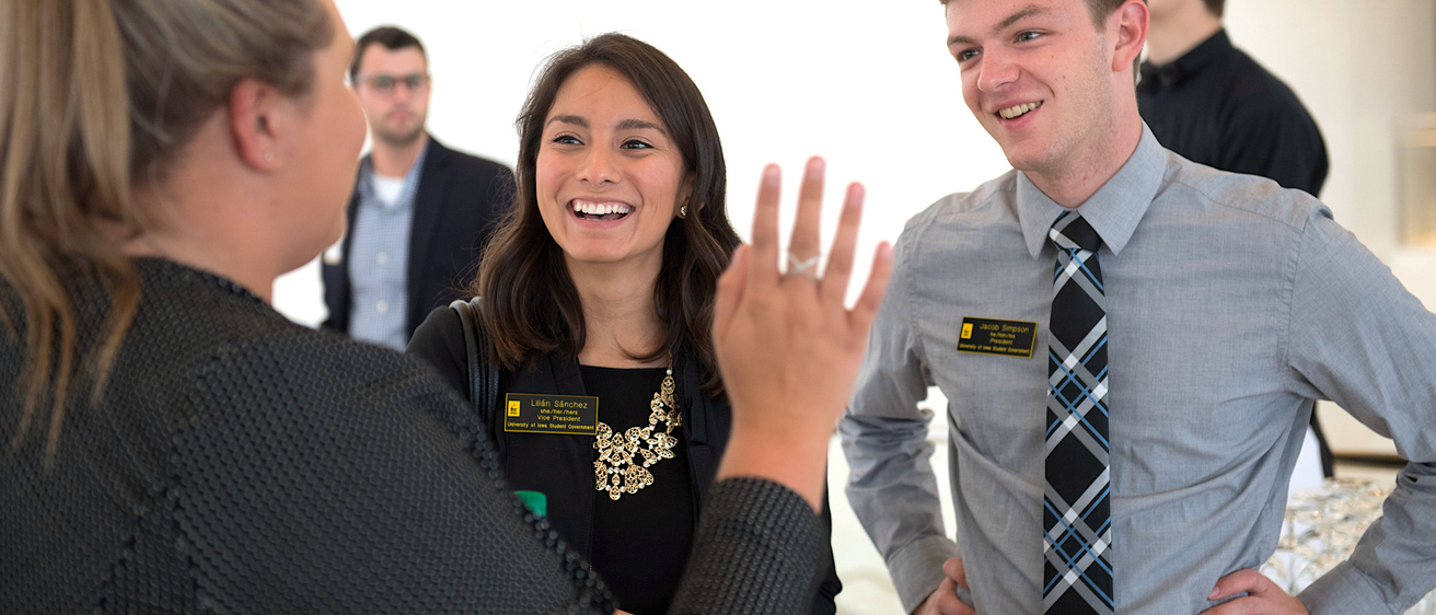 Three people in business attire talking at an event.